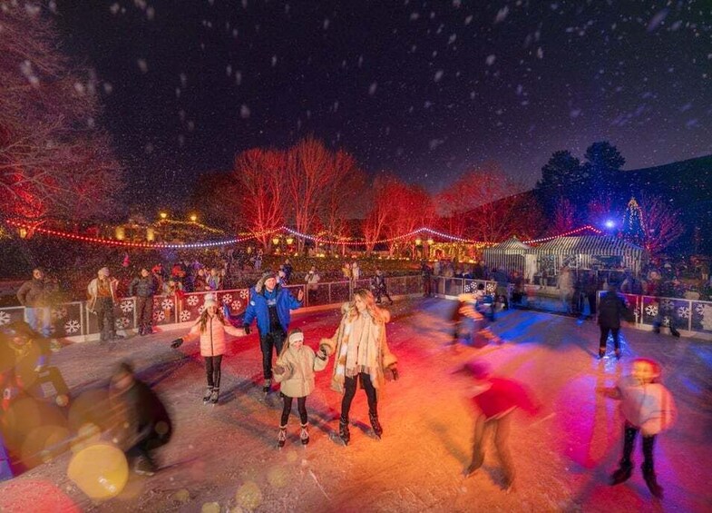 Mensen schaatsen op een ijsbaan in de nacht, met kleurrijke verlichting en sneeuw. 5
