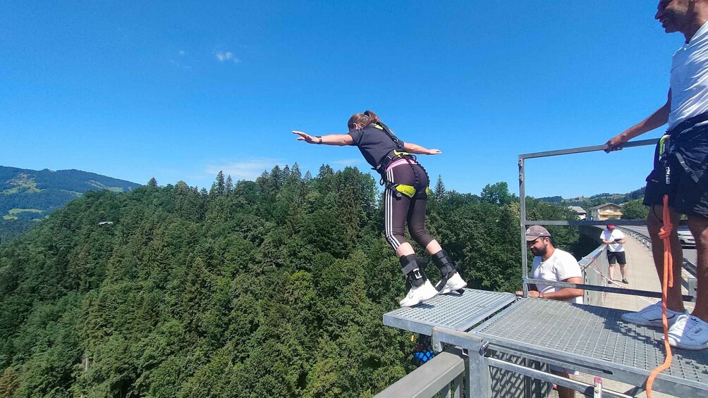 A person balancing on a narrow beam with a forested mountain in the background. 3