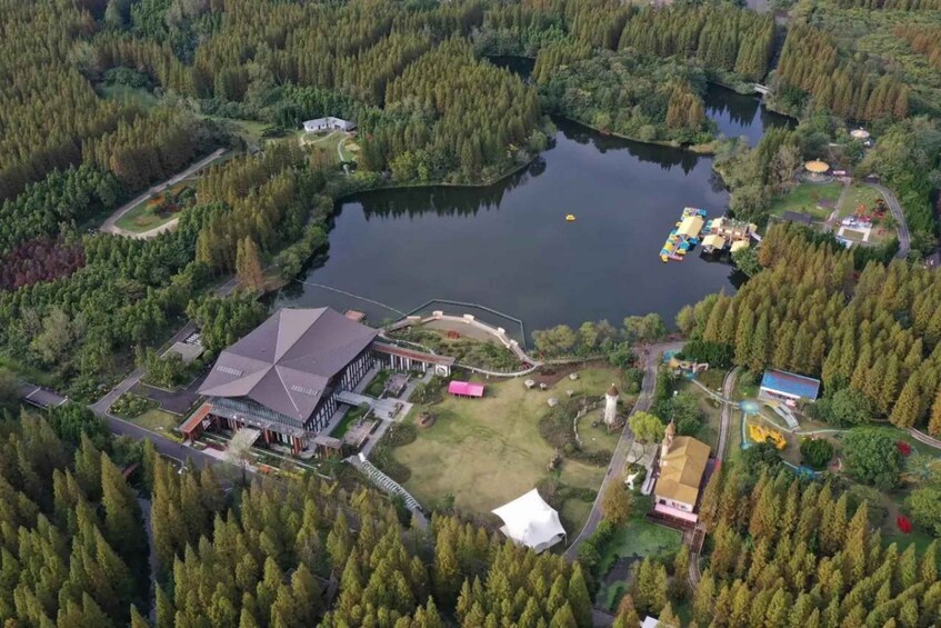 An aerial view of a lakeside property with a large building, a dock, and surrounding forest. 1
