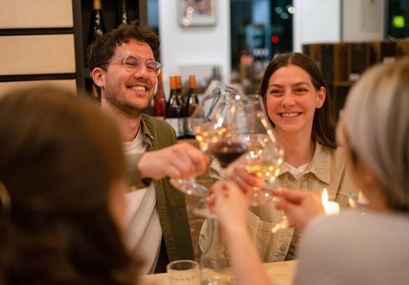 A group of people toasting with wine glasses at a table in a restaurant. 1