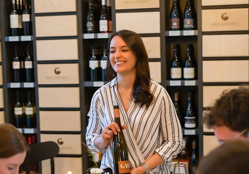 A person holding a wine bottle in a room with shelves of wine bottles. 2