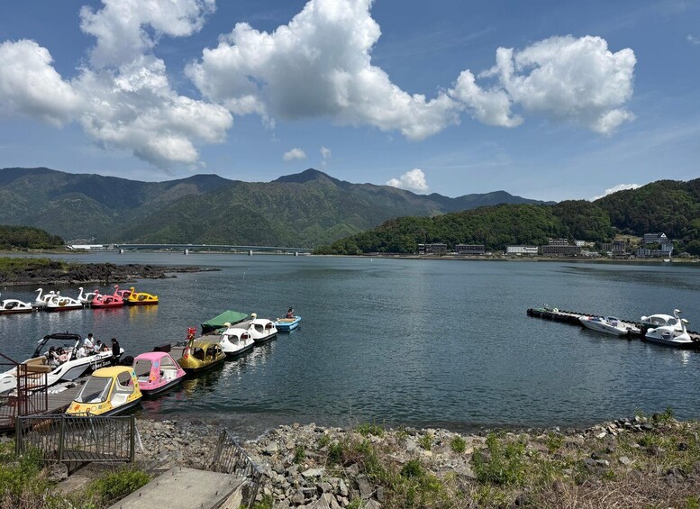 A lake with boats, mountains, and a bridge in the background. 5