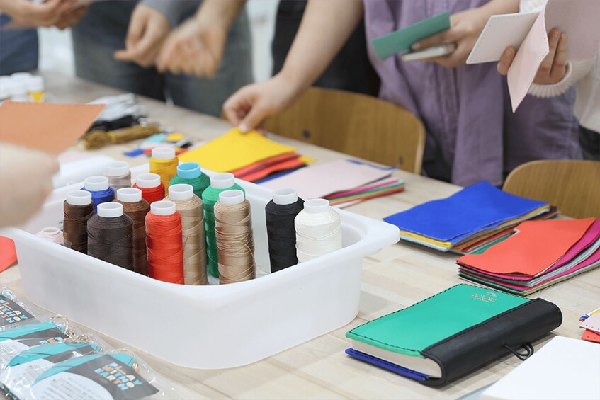 A table with spools of thread, fabric, and sewing materials. 3