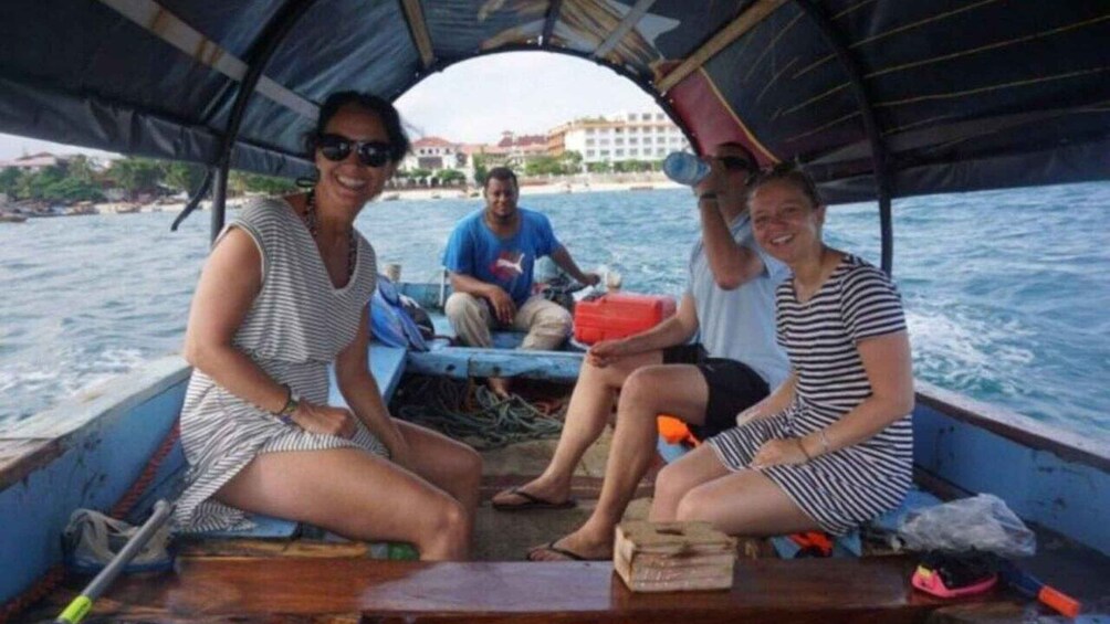Three people on a boat with a cityscape in the background. 2