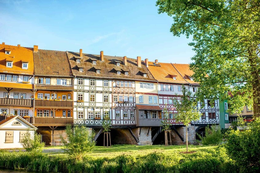 A row of traditional half-timbered houses with a bridge and lush greenery in the foreground. 3