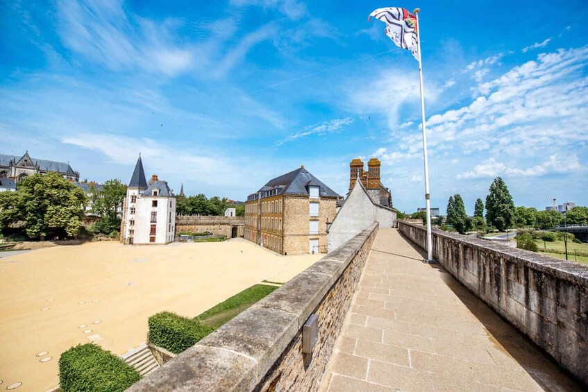A stone bridge with a flag, historic buildings, and a clear sky. 2