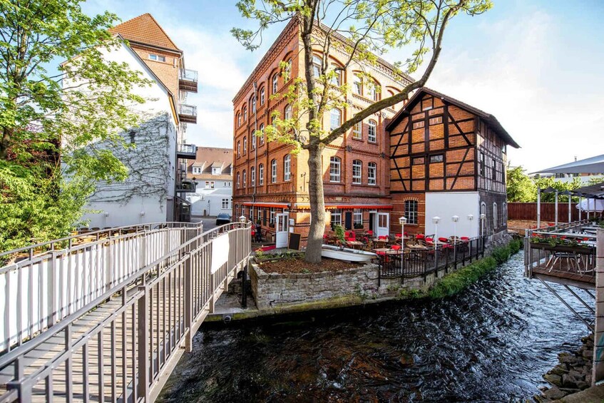 A riverside building with a tree in front, a bridge, and a restaurant with outdoor seating. 5