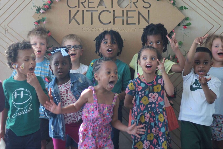 A group of children in front of a sign that reads 'CREATORS KITCHEN.' 2