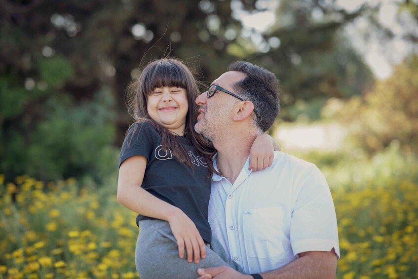 A person holding a child in a field with yellow flowers. 2