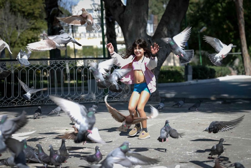 A person interacting with pigeons in an outdoor setting. 3