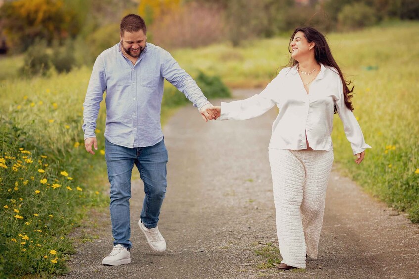 Two people walking on a gravel path surrounded by grass and yellow flowers. 5