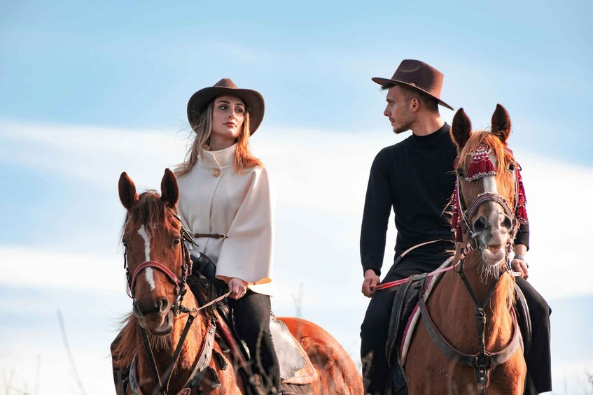 Two people riding horses in an open field. 1
