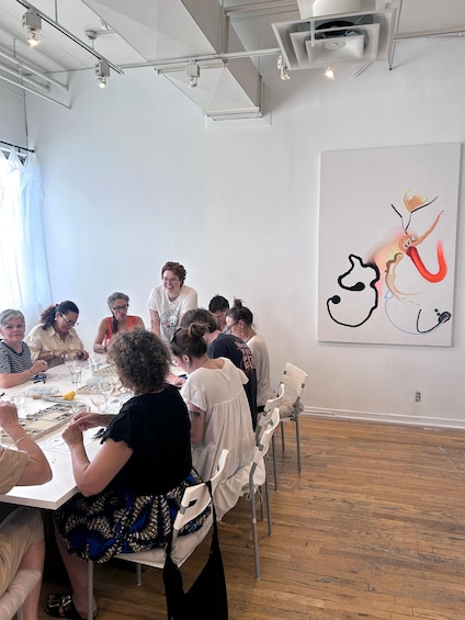 A group of people engaged in a craft activity around a table with various tools and materials. 2