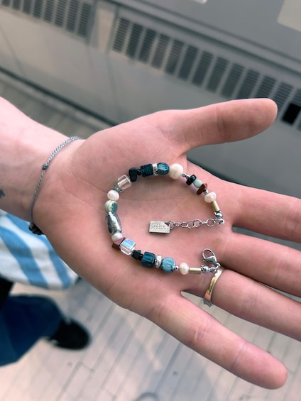 A hand holding a bracelet with various beads and a keychain with a name tag. 5