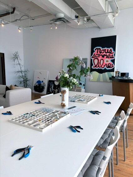 A modern office space with a white table displaying organized craft supplies, a decorative plant, and a vibrant poster on the wall. 5