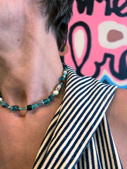 A person wearing a striped garment with a beaded necklace. 1