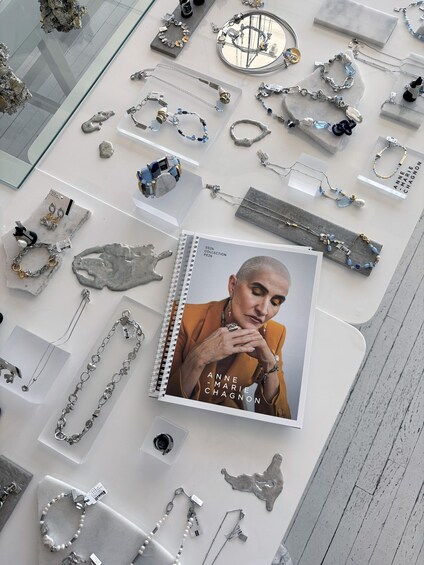 A jewelry display with various necklaces, bracelets, and a book titled 'Anne-Marie Chagnon.' 4