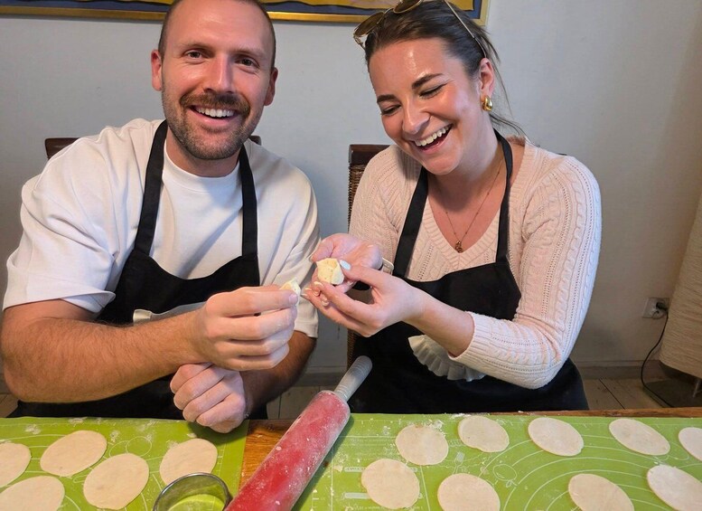 Two people preparing food, with dough on a green mat and a rolling pin. 4