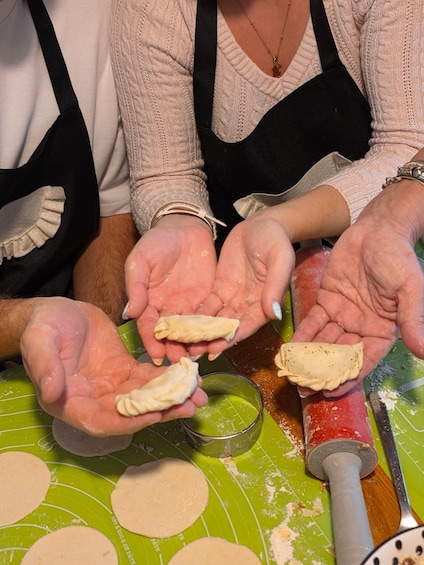 Two people rolling out dough on a green mat. 2