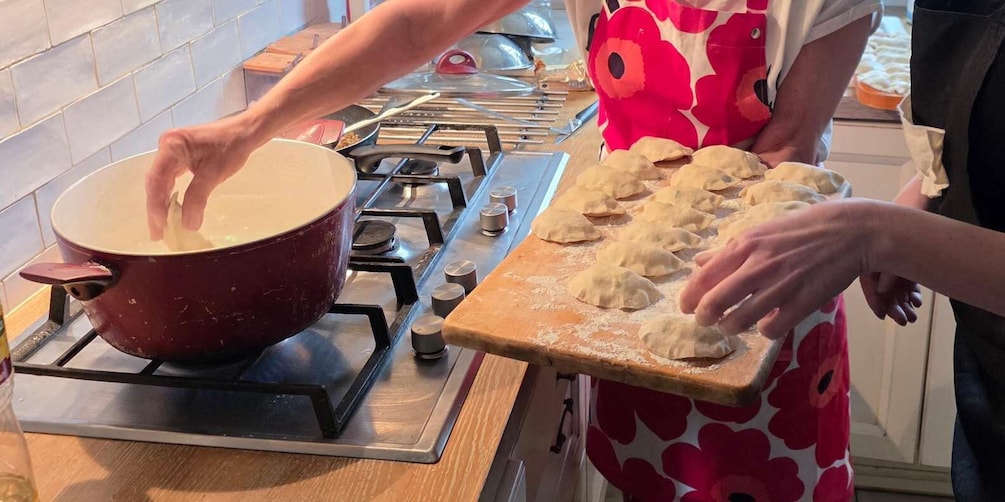 A person cooking on a stove with a pot and preparing dough on a wooden board. 5