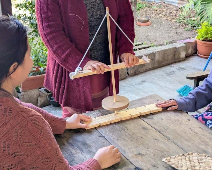 A person demonstrating a balance scale with wooden blocks and a pendulum. 3