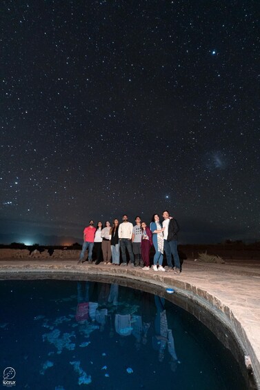 A group of people standing by a pool under a starry night sky. 3