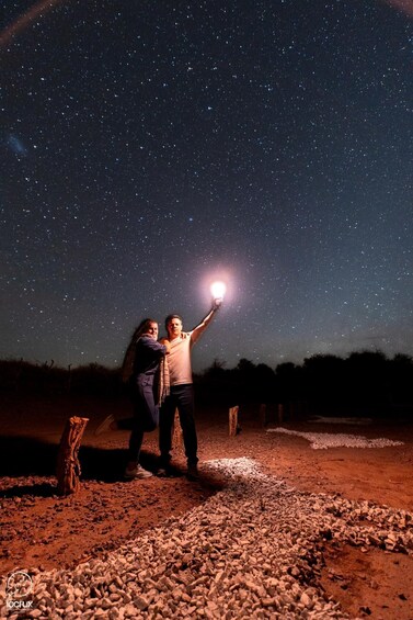 Two people under a starry sky, one holding a flashlight. 2