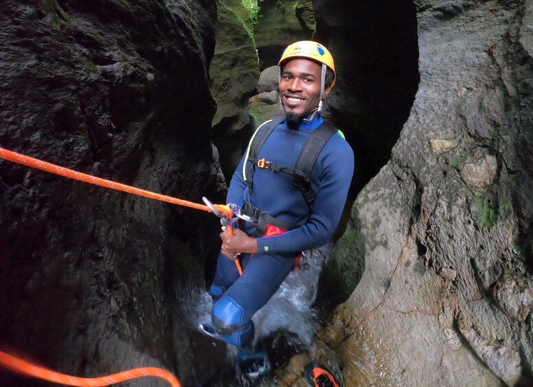 A person rappelling in a rocky cave with a helmet and harness. 5