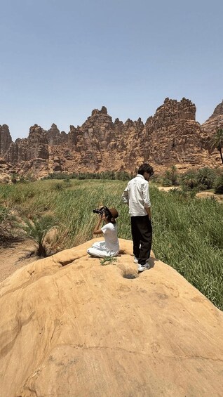 Two people in a desert landscape with rocky formations and sparse vegetation. 3