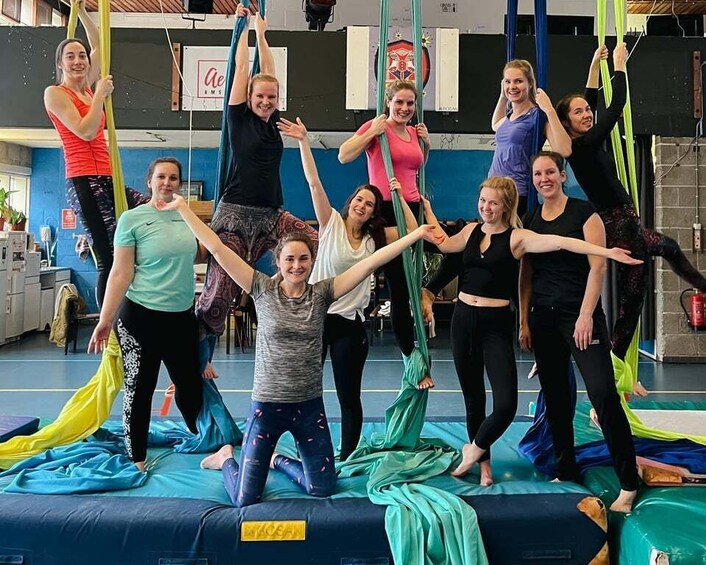 A group of people practicing aerial yoga in a gym. 2