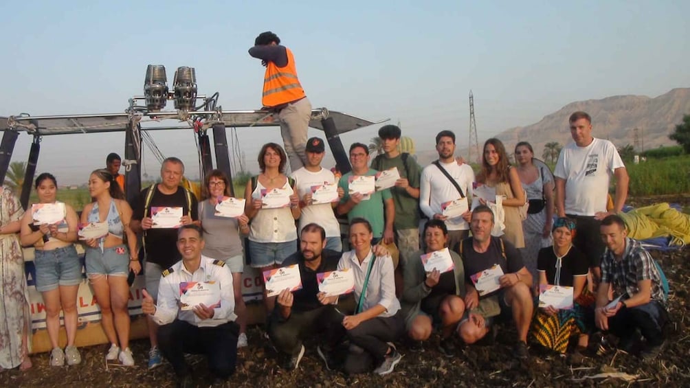 A group of people posing with certificates in an outdoor setting with mountains in the background. 3
