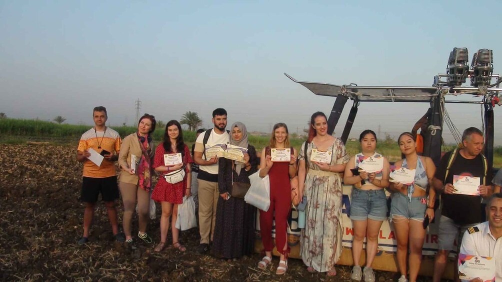 A group of people standing in a field with agricultural machinery. 2