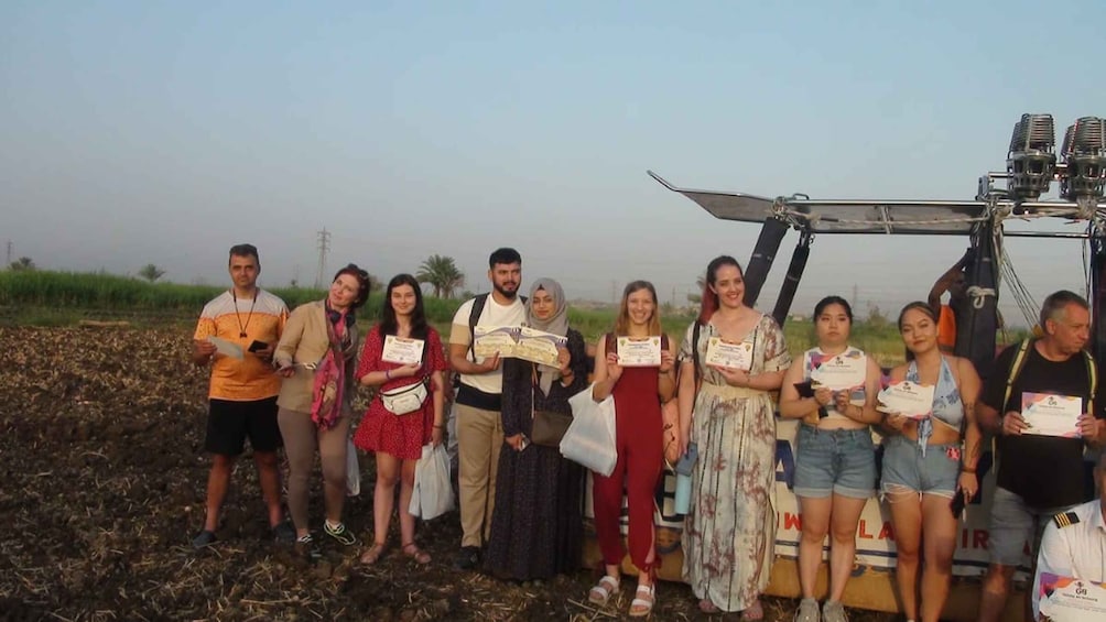 A group of people standing in a field with a large piece of machinery in the background. 5