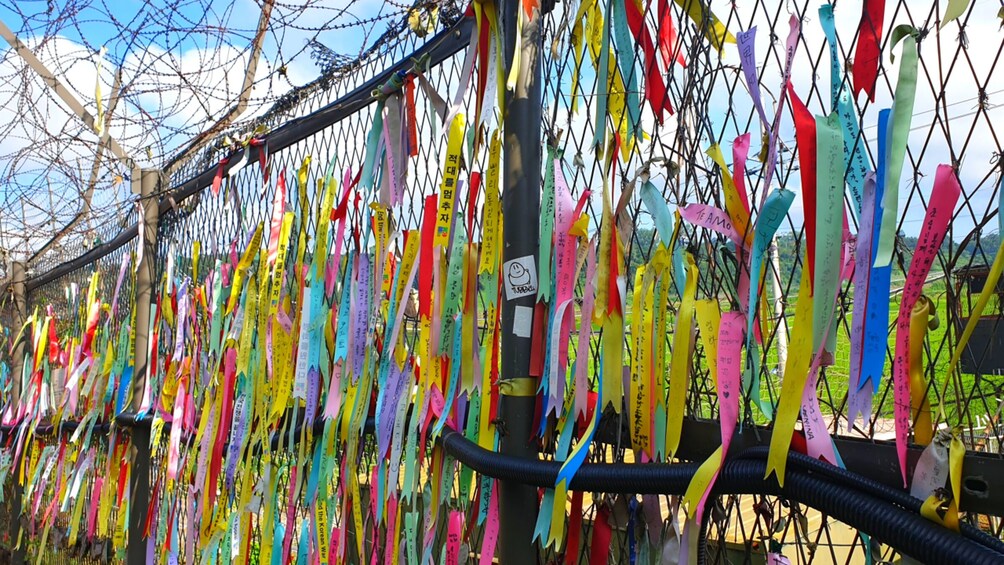 A fence adorned with colorful ribbons and tags. 5