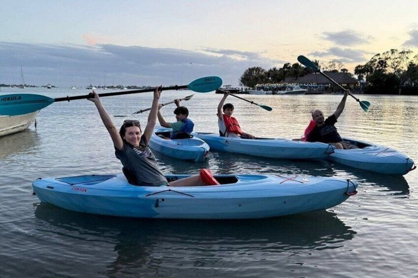 People kayaking on calm water with a marina in the background. 1
