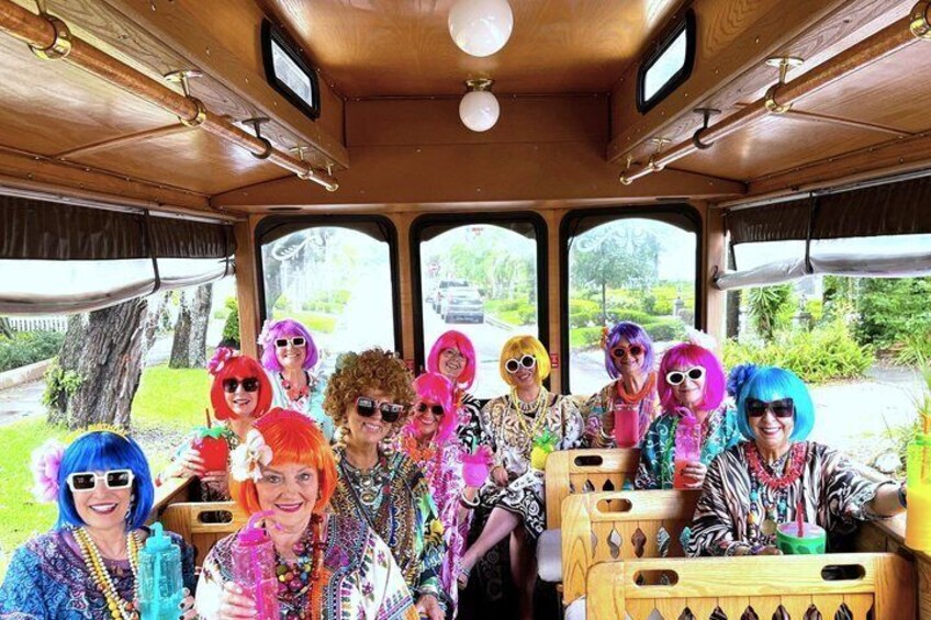 A group of people in colorful wigs and costumes inside a vehicle. 2
