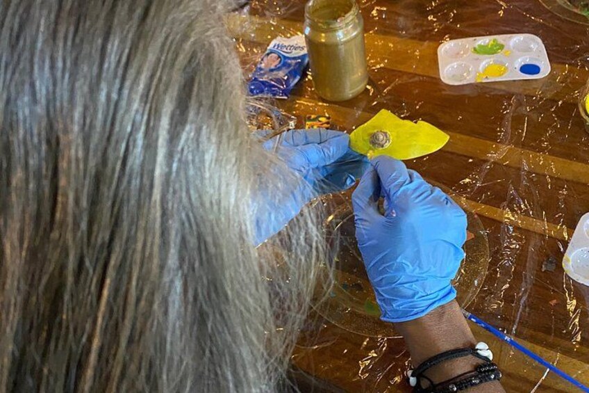 A person painting a yellow object with blue gloves on a table covered with a plastic sheet. 4