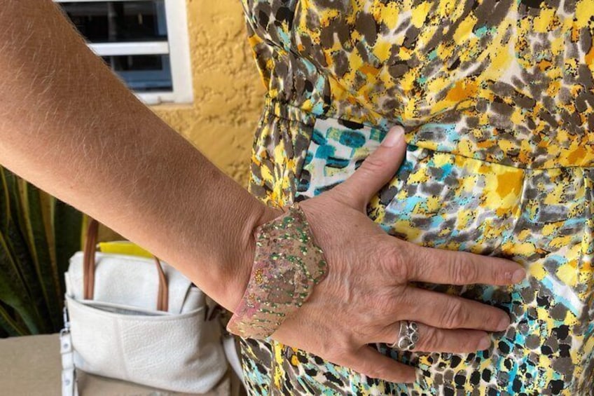 A hand on a patterned fabric, a white bag, and a window with blinds. 3