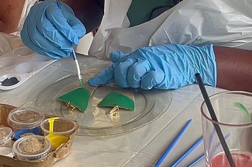 A person wearing blue gloves handling a green object on a lab bench with various containers and tools. 1