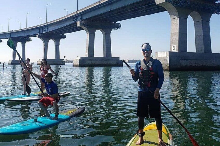 People paddleboarding on a river with a bridge in the background. 2