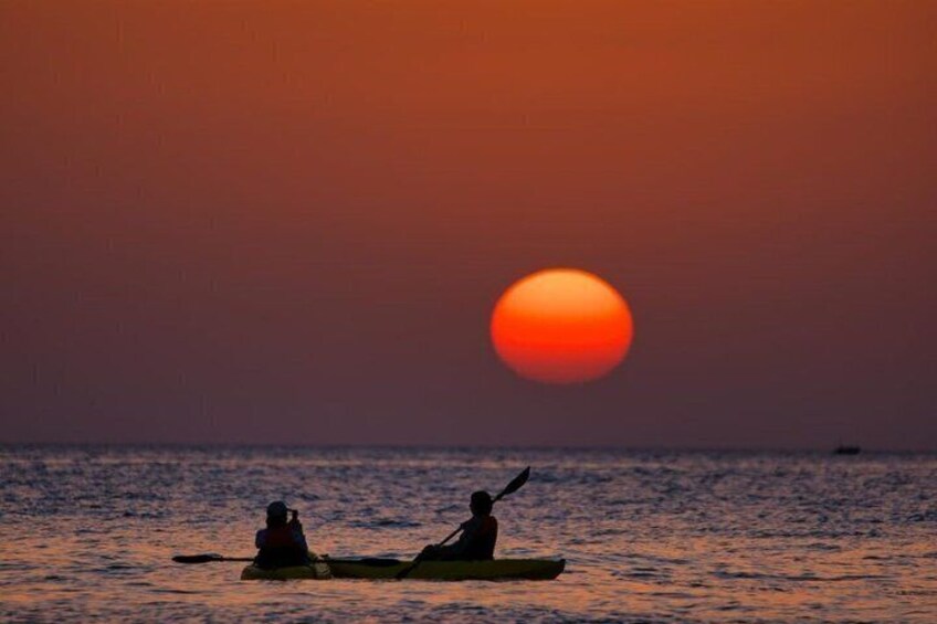 Two people kayaking on a calm sea during sunset. 4
