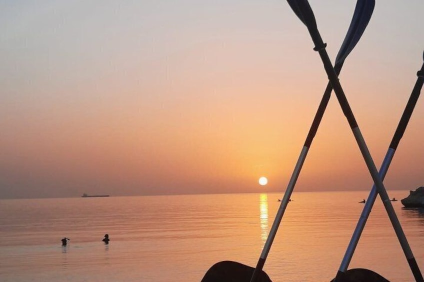 A sunset over calm waters with a boat and a person swimming. 5