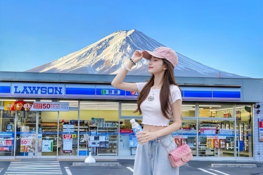 A person standing in front of a Lawson convenience store with a mountain in the background. 1