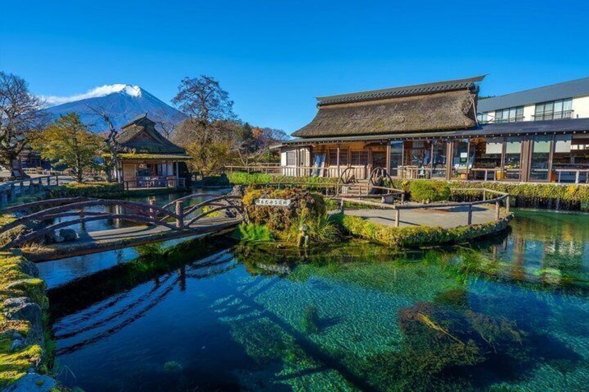A traditional Japanese garden with a clear pond, a bridge, and buildings in the background. 5