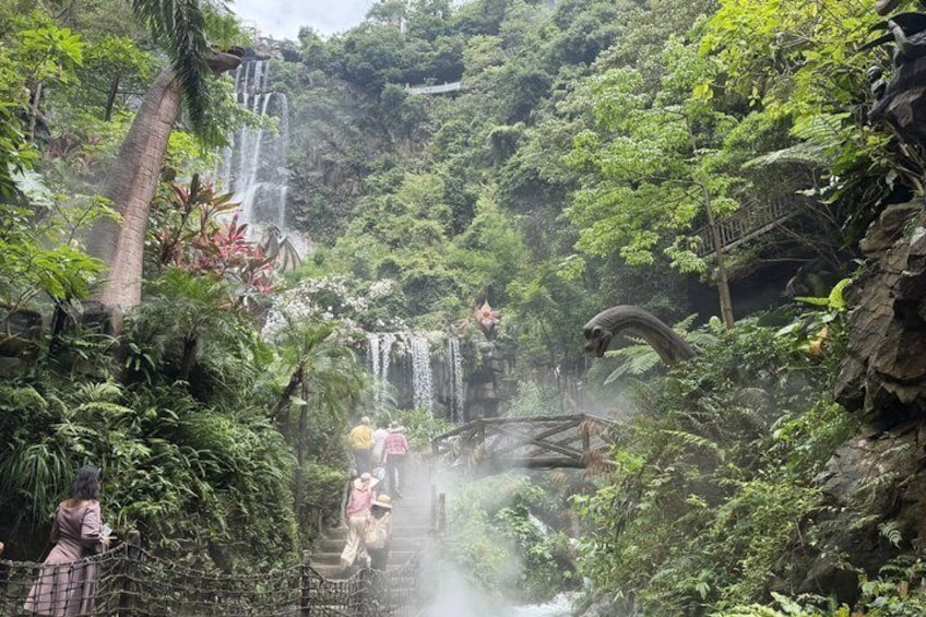 A waterfall surrounded by lush greenery and a wooden bridge. 3