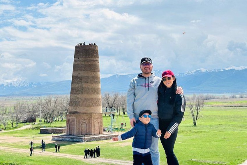 A family standing in front of a tall tower with a mountainous backdrop. 2