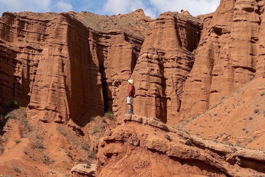 A person standing on a rocky outcrop with red rock formations in the background. 5