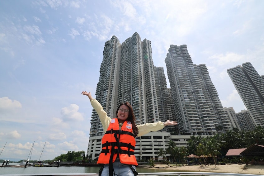 A person in a life jacket with arms outstretched, a high-rise building, a beach, and palm trees in the background. 3