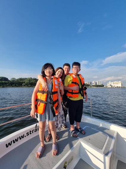 A group of people on a boat wearing life jackets, with a calm lake and buildings in the background. 4