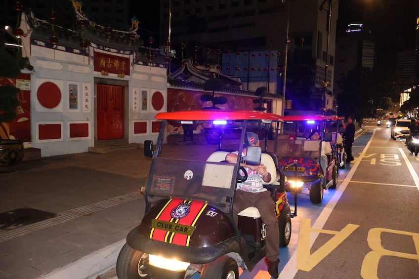 A street with a Club Car vehicle and a person riding it. 2